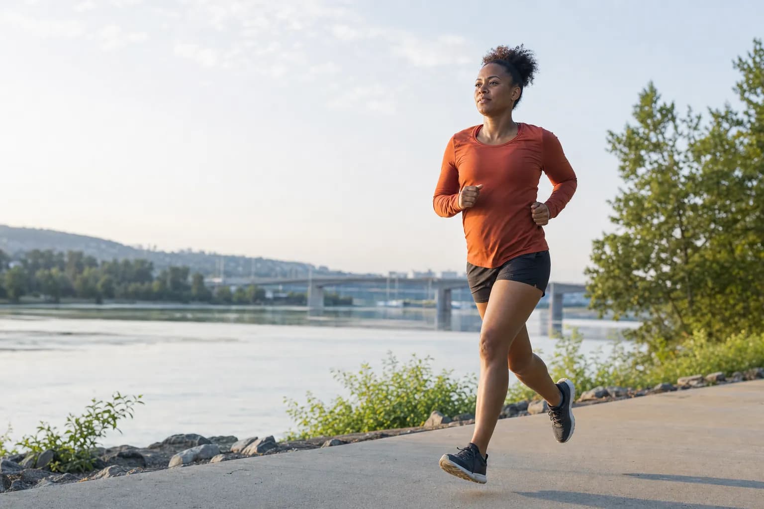A woman running along a riverside path in the morning